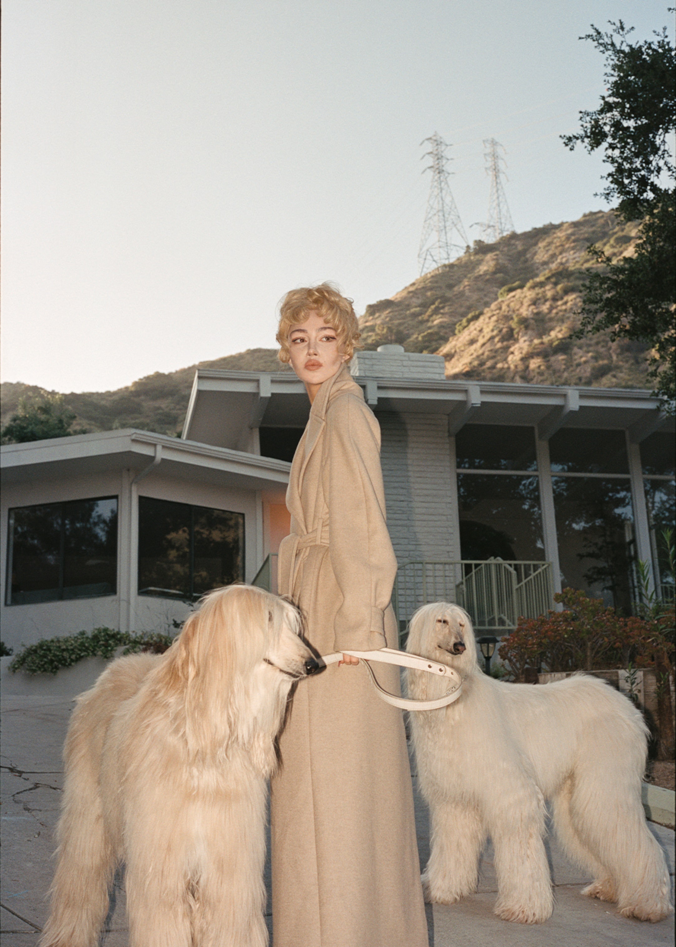 Woman in beige coat walking two dogs