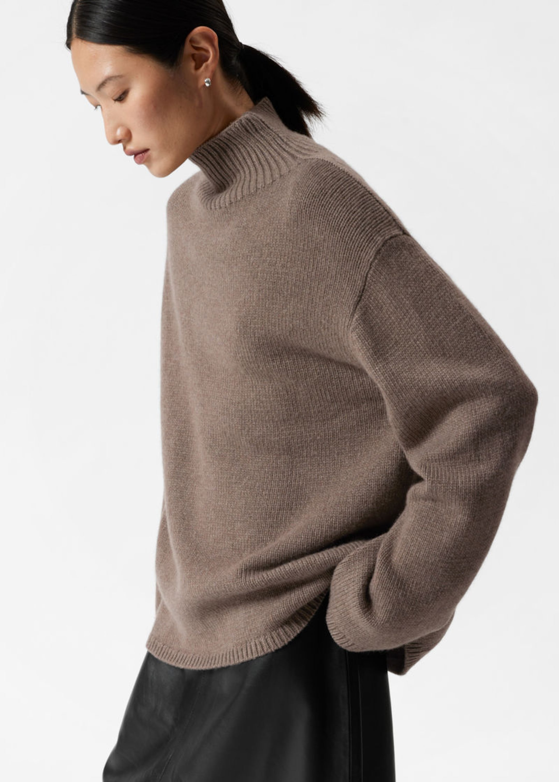 woman in dark mole cashmere sweater with high neck standing on the side looking down